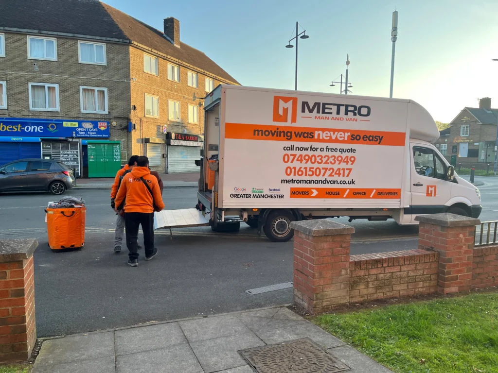 A friendly team from a furniture donation collection Manchester service carefully lifts a three-seater sofa out of a home.
