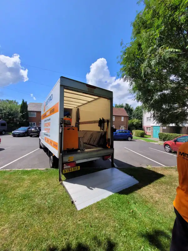 smiling Metro Man and van team member giving a friendly wave to a family, showcasing the supportive nature of a Manchester family move.
