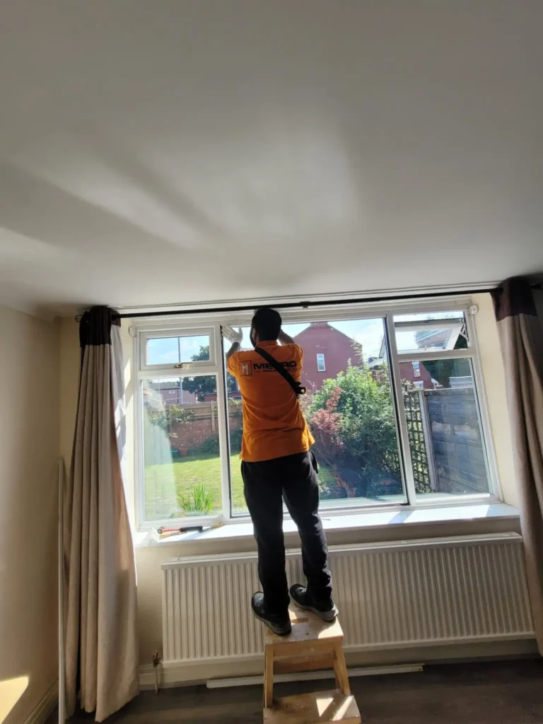 A Metro Man and van team member expertly installing new blinds in a customer's Manchester home, ensuring a perfect fit.